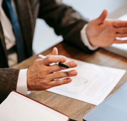 Professional discussing documents over a wooden table in an office setting.